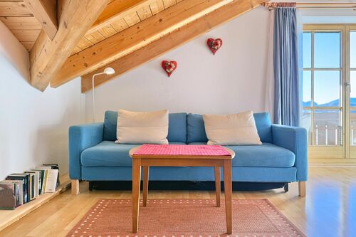 Wohnzimmer mit gemütlicher Couch, Couchtisch und Balkon mit Berglick