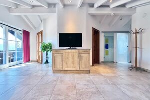 Wohnbereich mit TV-Sideboard und Balkon mit Berg- und Seeblick