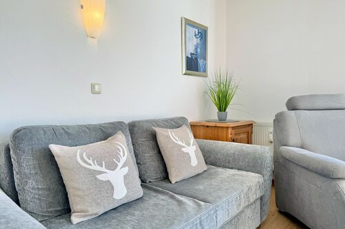 Wohnzimmer mit Couch, Sessel und Wanddekoration